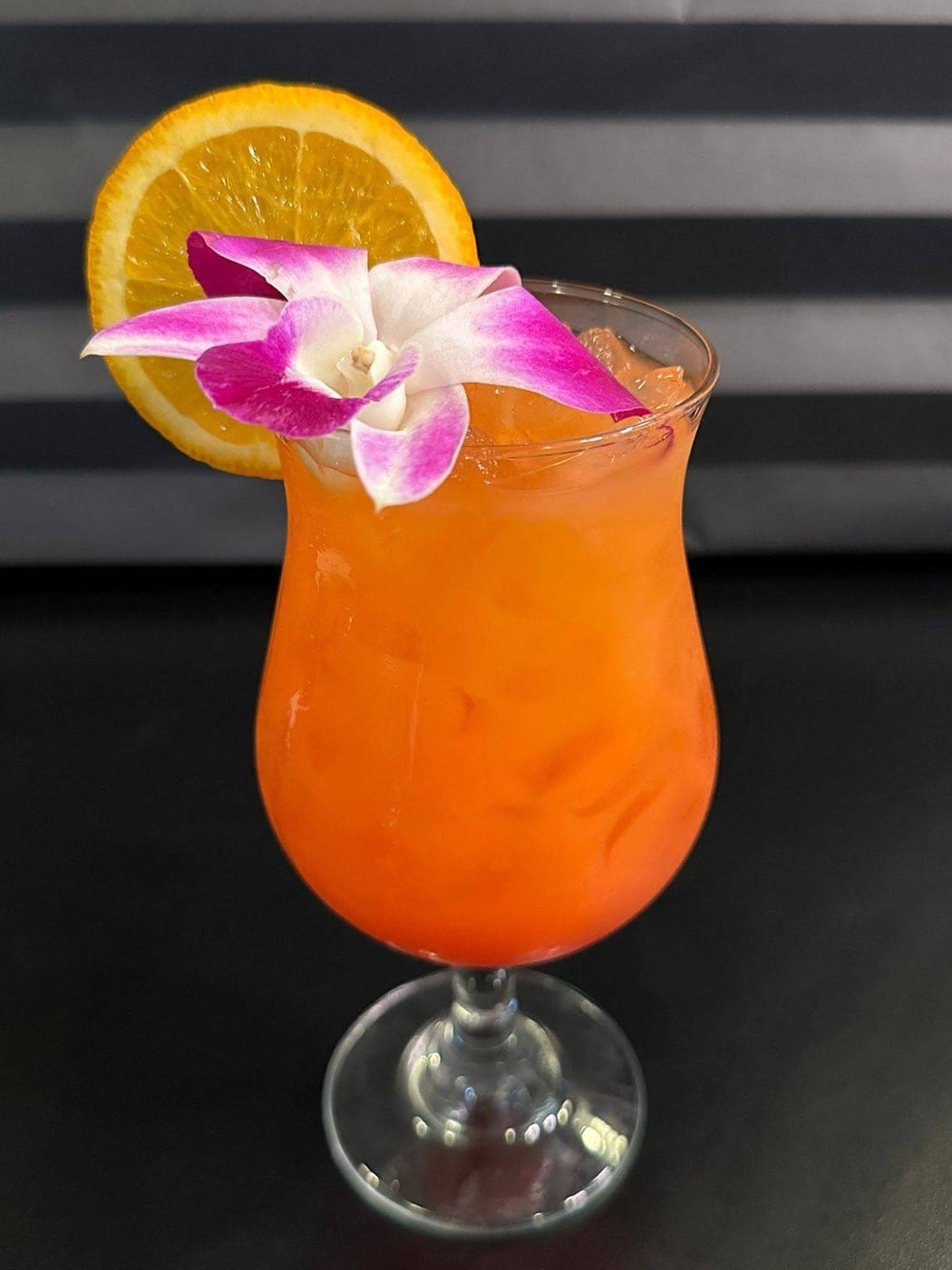 Tropical orange cocktail with orchid