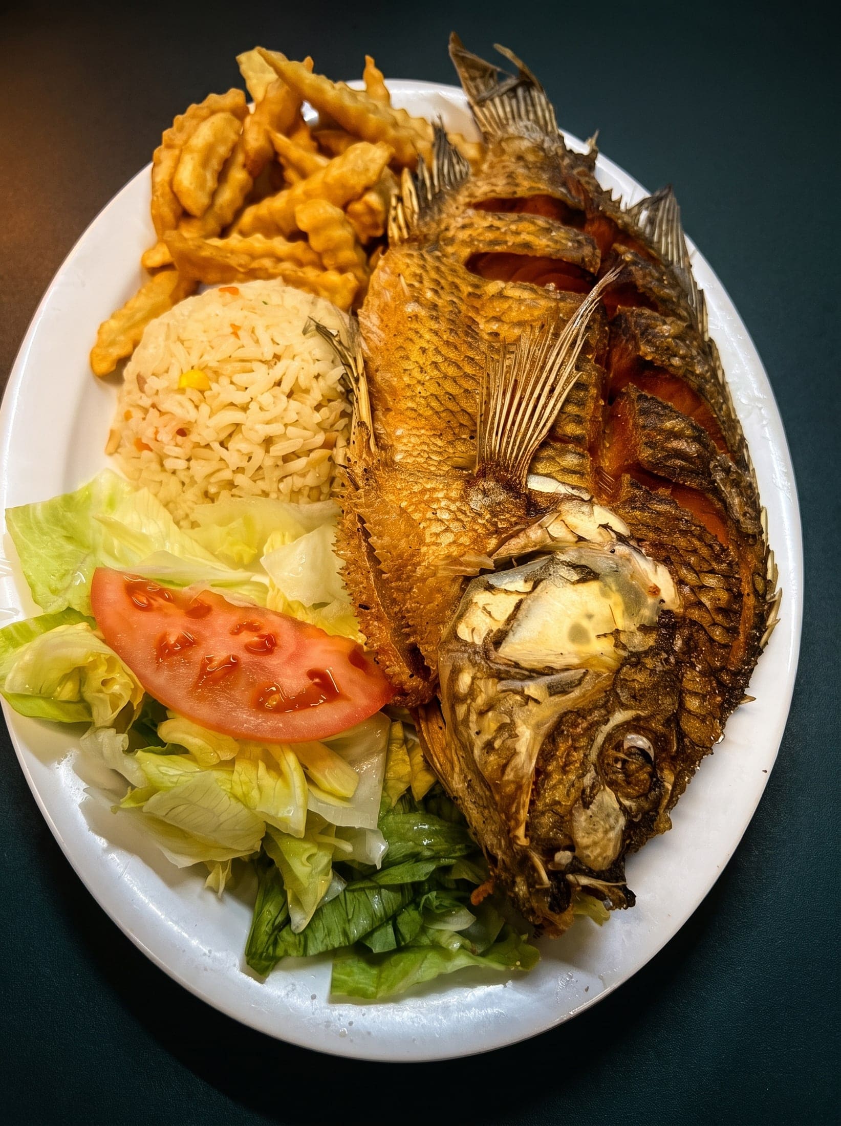Pescado entero frito con arroz, papas y ensalada
