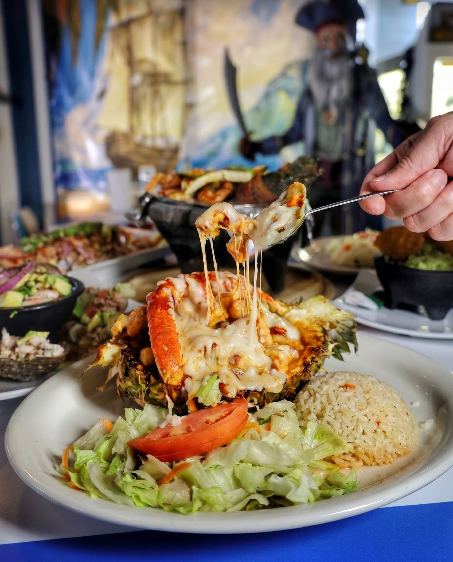Piña a la Salsa Diablo — Grilled pineapple loaded with hot seafood, drowned in salsa diabla and melted cheese that pulls. It arrives at your table steaming — and yes, it's as good as it looks.